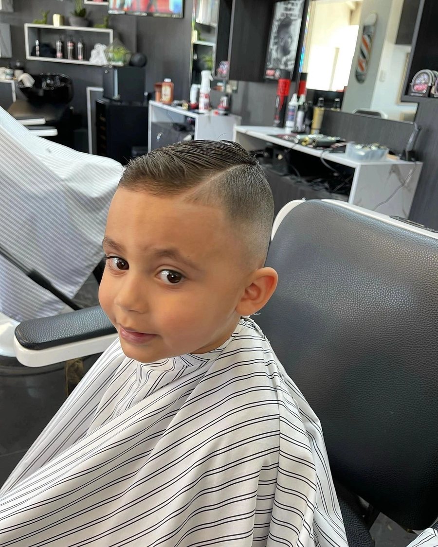 Young boy facing the camera in the barber chair after a short crop.