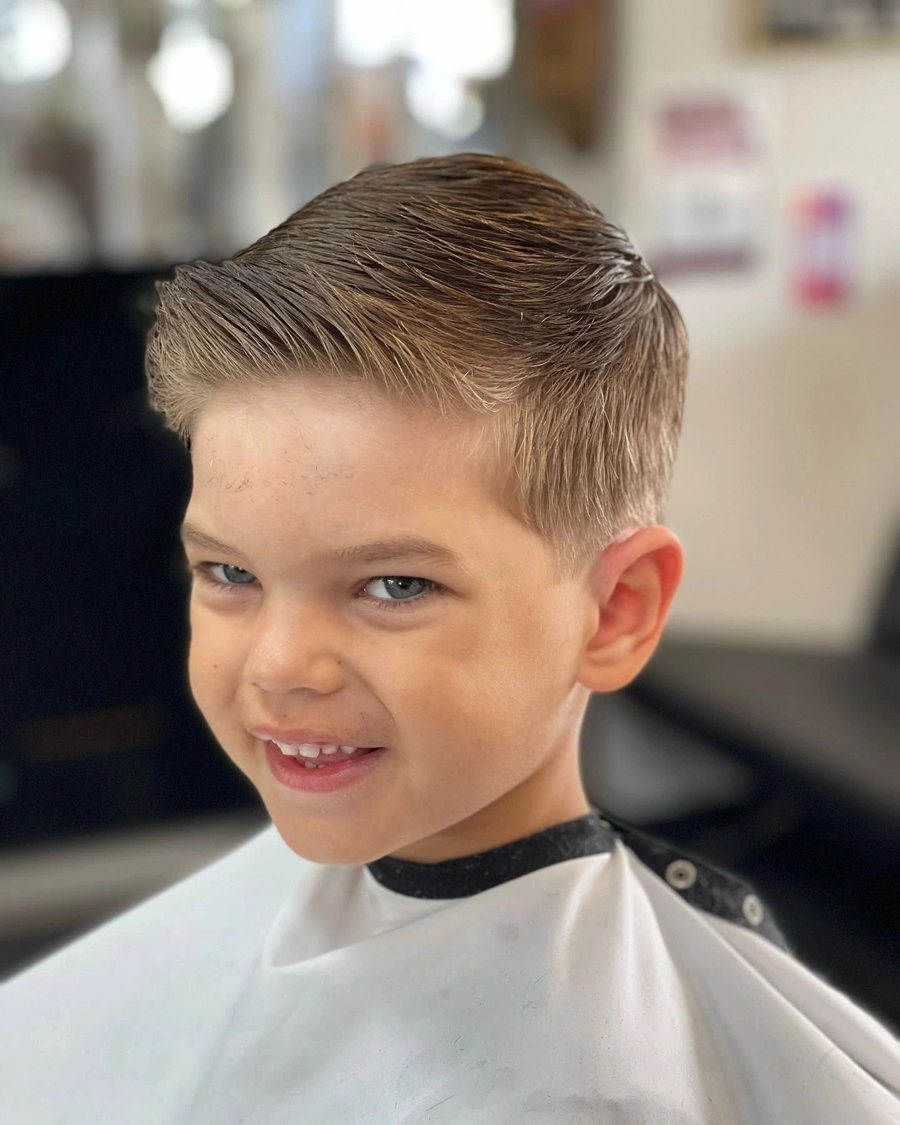 Young boy smiling after a short textured cut with a tapered fade.