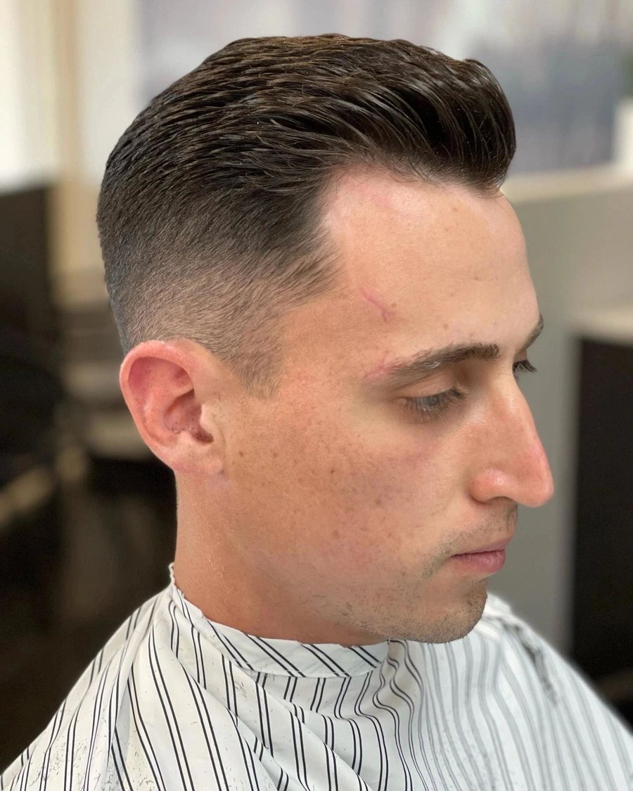 Man with a textured quiff and a clean taper fade through the sides.